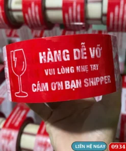 Băng keo in hàng dễ vỡ màu đỏ với nội dung “Vui lòng nhẹ tay – Cảm ơn bạn shipper” dùng đóng gói hàng hóa.