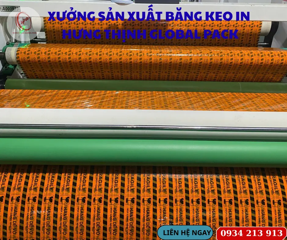 Hệ thống máy phân cuộn băng keo công suất lớn đang sản xuất băng keo in chữ cảnh báo "Hàng dễ vỡ - Fragile" sắc nét tại nhà xưởng Hưng Thịnh Global Pack.