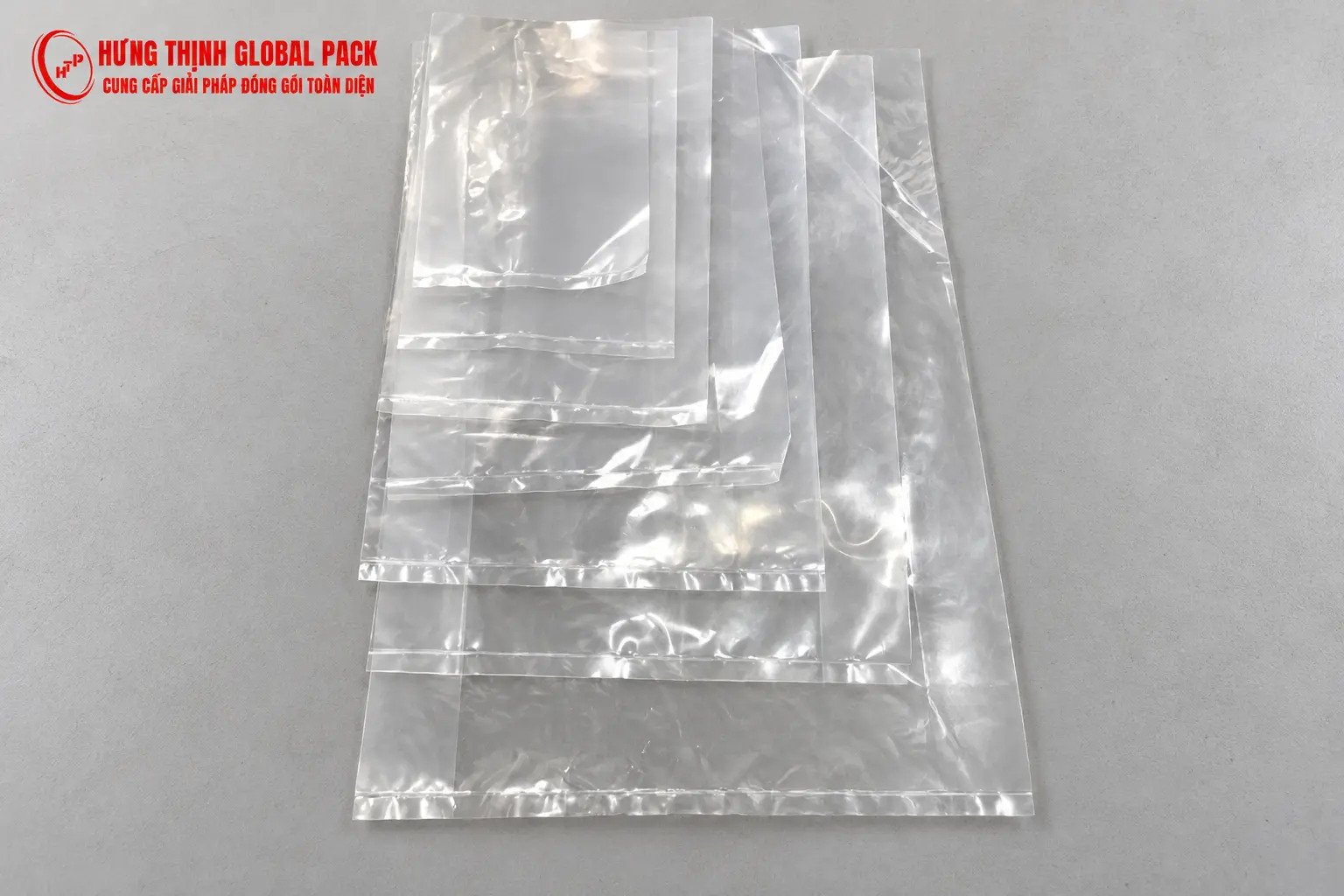 Các túi PE trong suốt miệng bằng nhiều kích thước xếp chồng từ nhỏ đến lớn trên nền xám sáng.